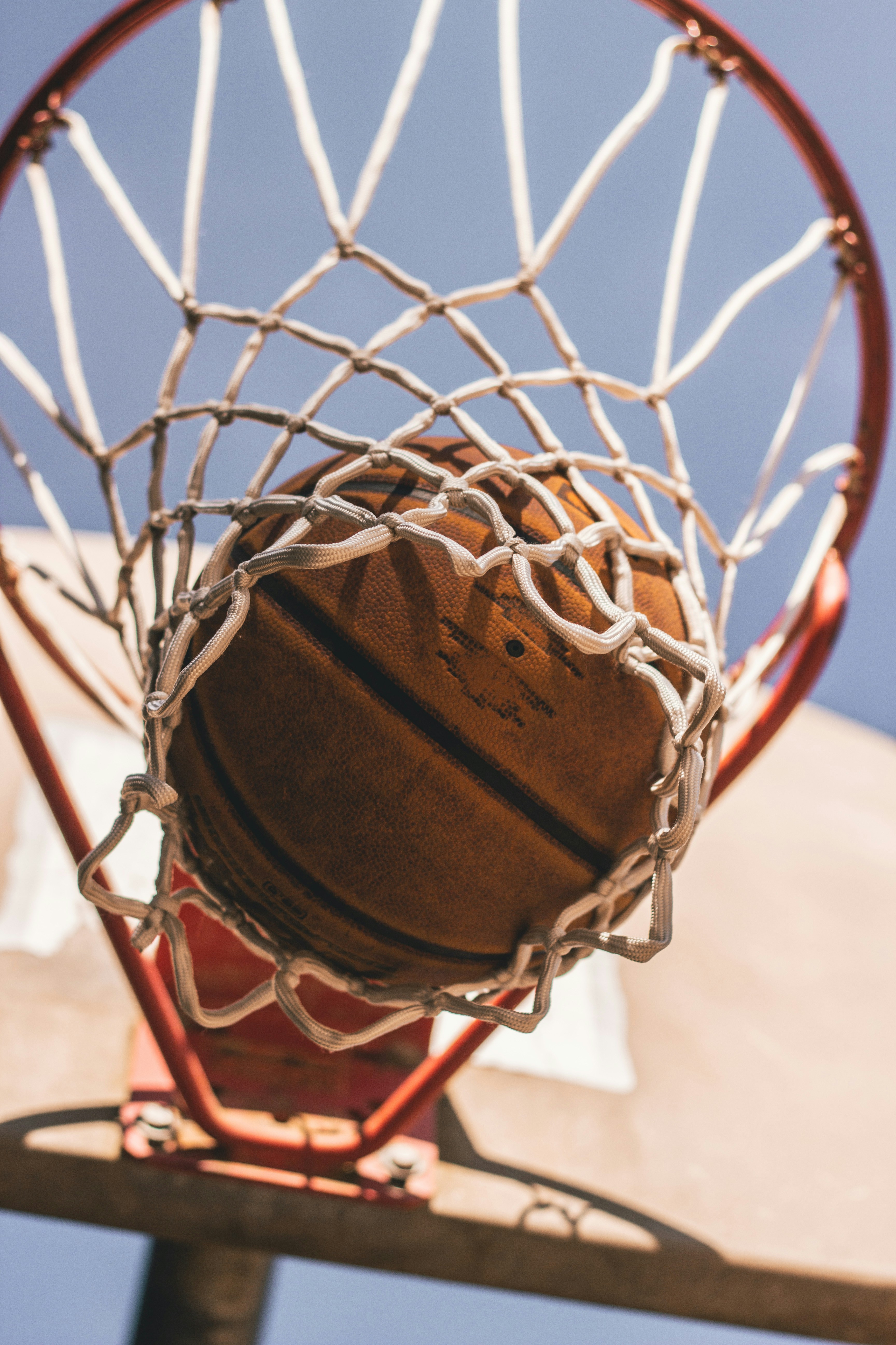 Photograph of basketball going through the rim.